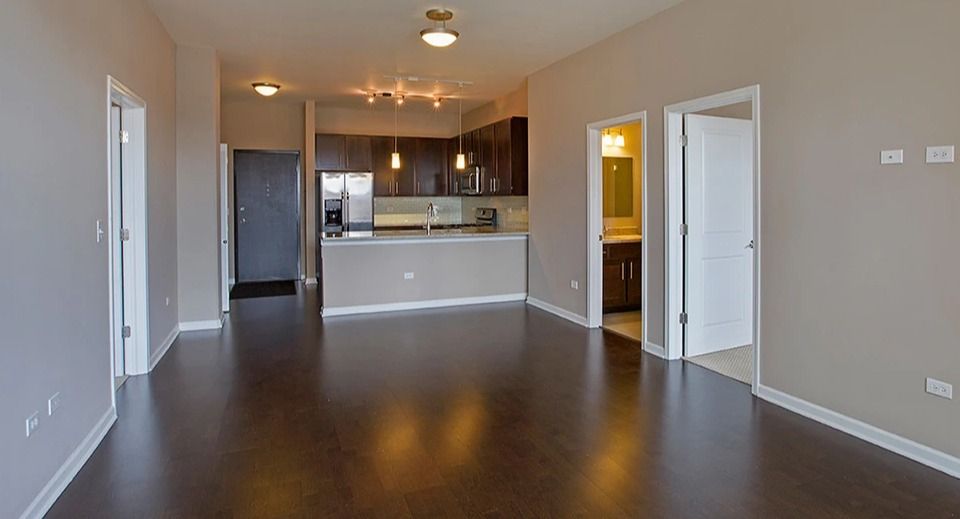 Spacious living room at The Shelby in Chicago, featuring hardwood floors and an open view into the modern kitchen area