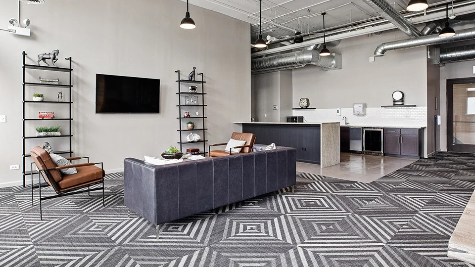 Expansive resident lounge at The Shelby in Chicago, featuring comfortable seating, a large TV, and a convenient kitchen area