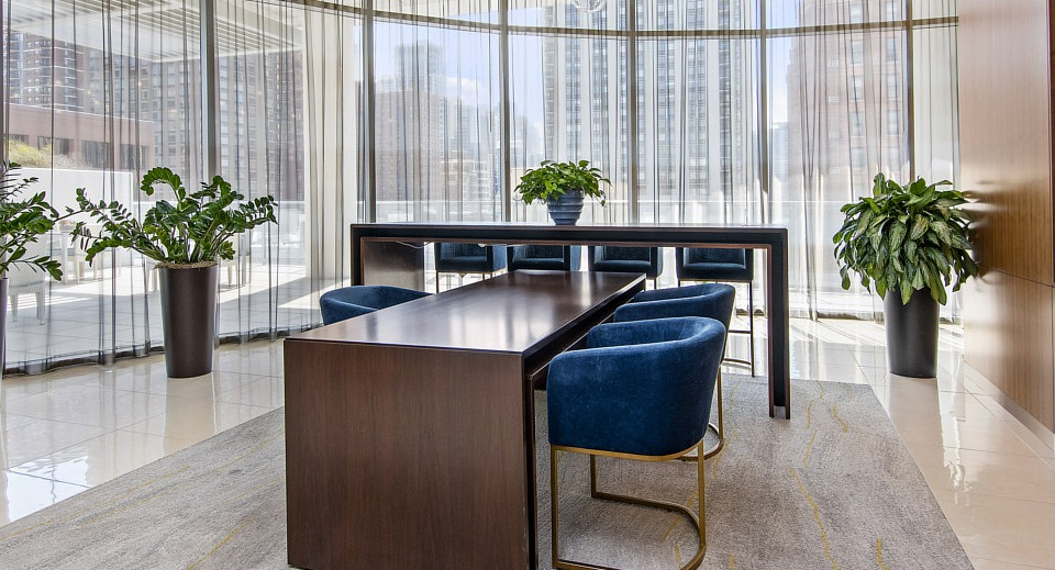 A modern resident conference room with a large table, blue velvet chairs, and vibrant artwork, ideal for meetings or study at The Sinclair in Chicago