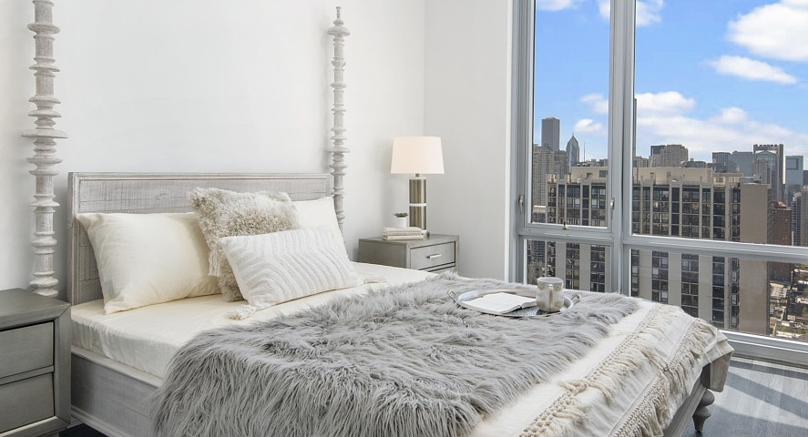 A chic and cozy bedroom with a comfortable bed, bedside tables, and a large window presenting captivating city views at The Sinclair in Chicago