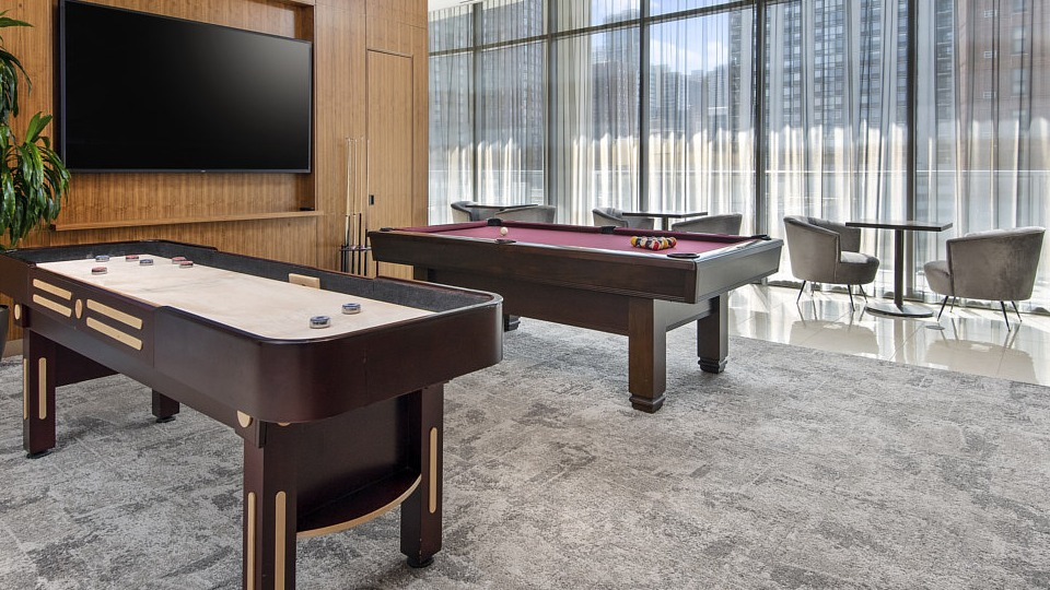 A stylish game room featuring a billiards table and a shuffleboard table, perfect for resident entertainment at The Sinclair in Chicago