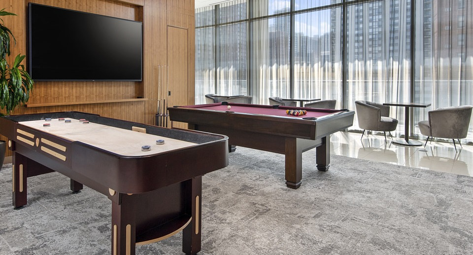 A stylish game room featuring a billiards table and a shuffleboard table, perfect for resident entertainment at The Sinclair in Chicago