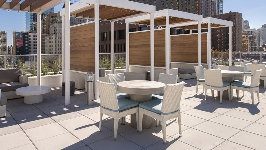 A stylish rooftop lounge area featuring comfortable outdoor sofas under pergolas and dining tables, perfect for socializing at The Sinclair in Chicago