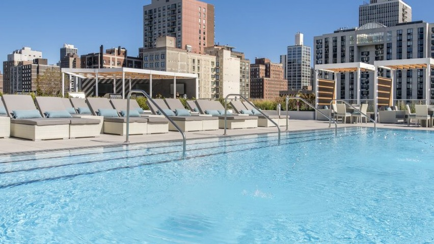 The sparkling rooftop swimming pool with comfortable lounge chairs and a breathtaking Chicago skyline backdrop at The Sinclair in Chicago