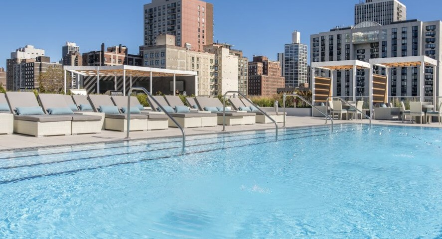 The sparkling rooftop swimming pool with comfortable lounge chairs and a breathtaking Chicago skyline backdrop at The Sinclair in Chicago