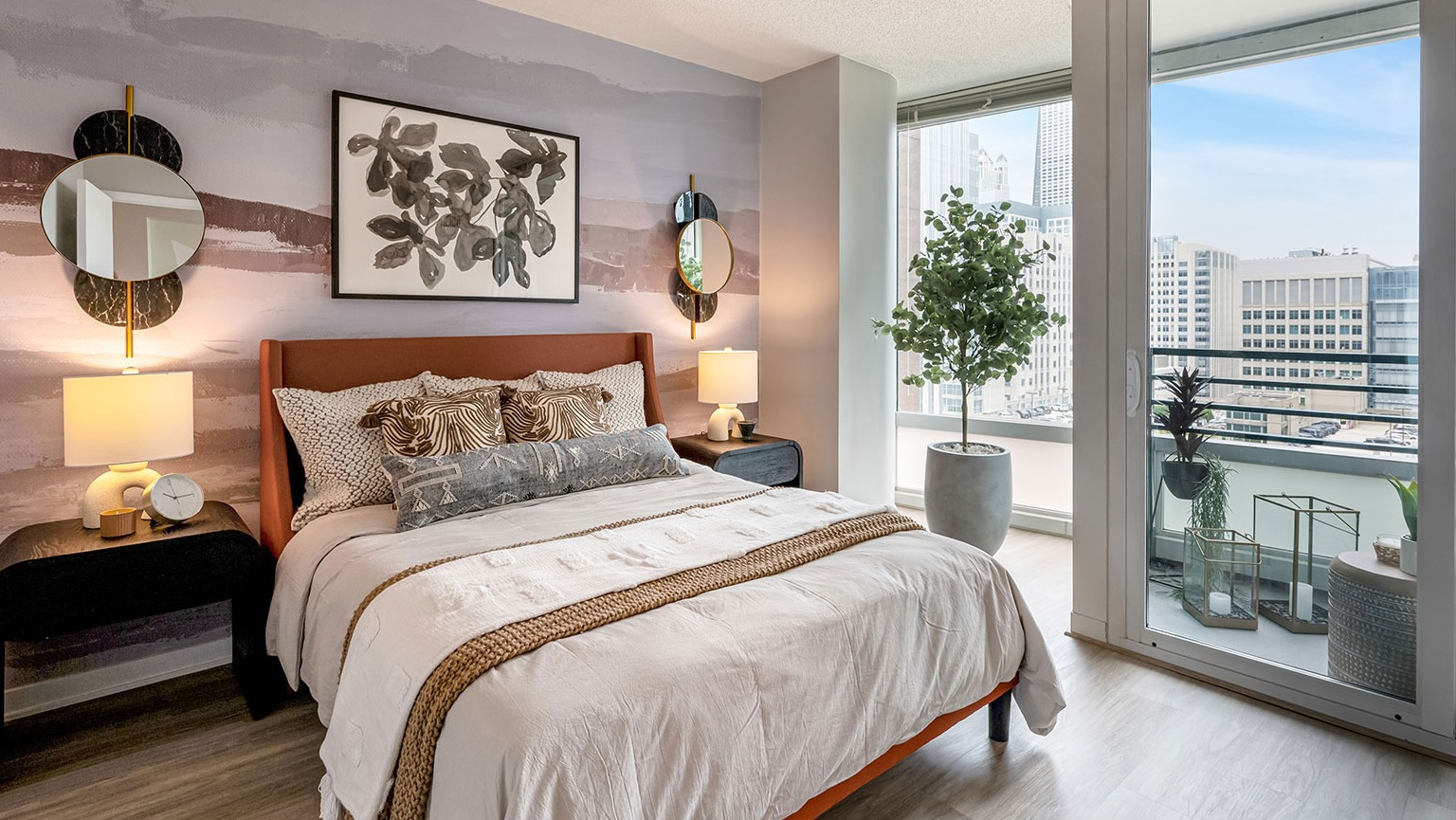 A chic bedroom with contemporary decor, access to a private balcony, and impressive city skyline views at The Streeter in Chicago