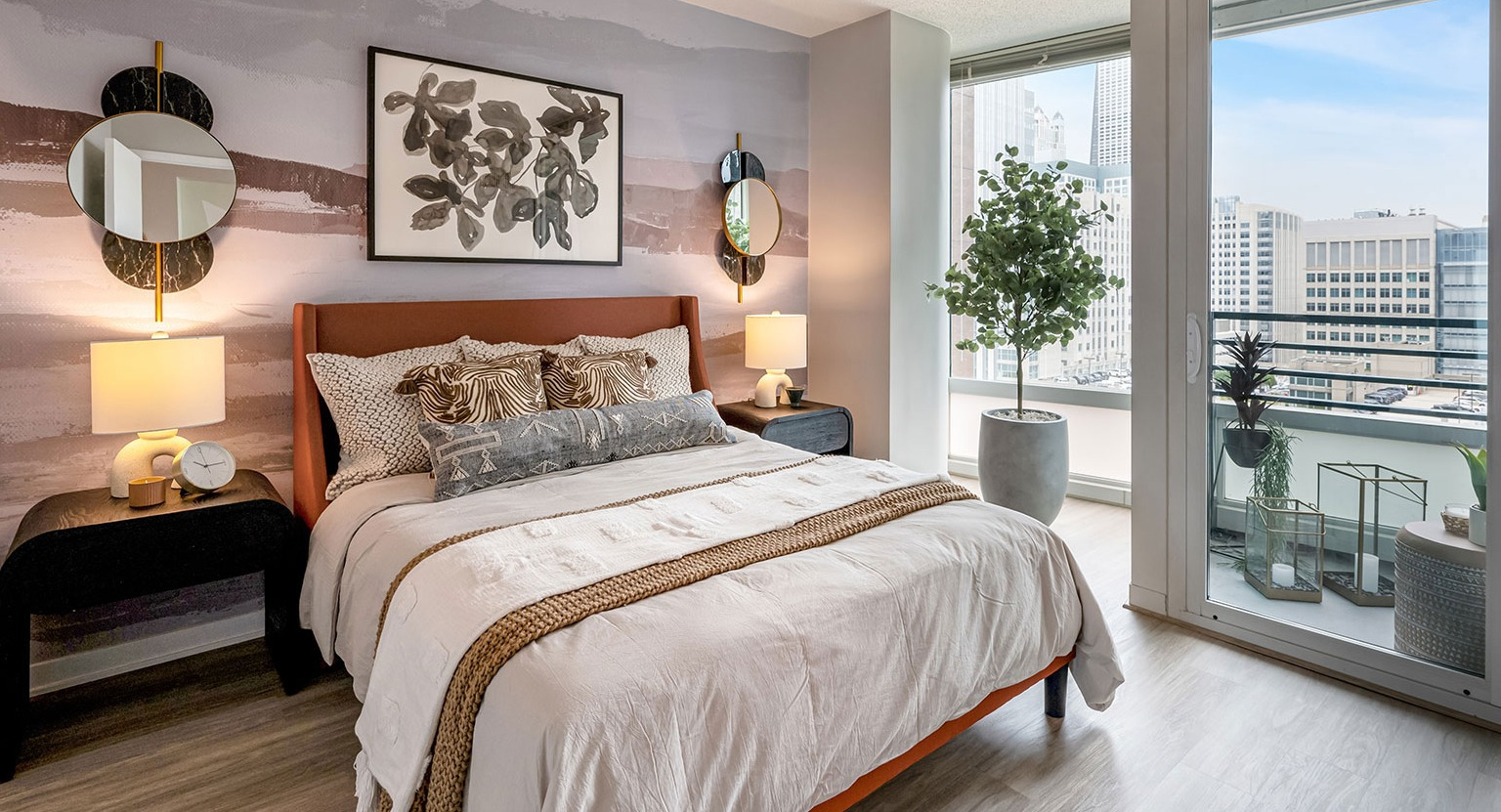 A chic bedroom with contemporary decor, access to a private balcony, and impressive city skyline views at The Streeter in Chicago