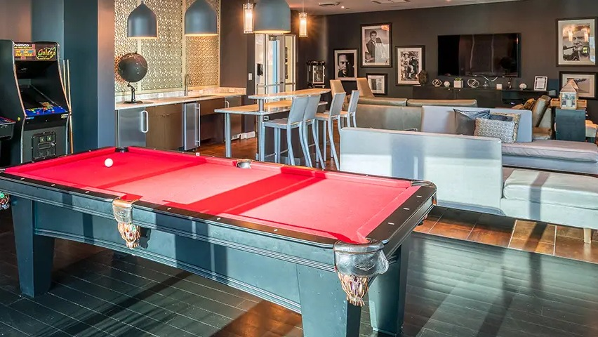A vibrant game room featuring a billiards table, classic arcade games, and a lounge area for resident entertainment at The Streeter in Chicago