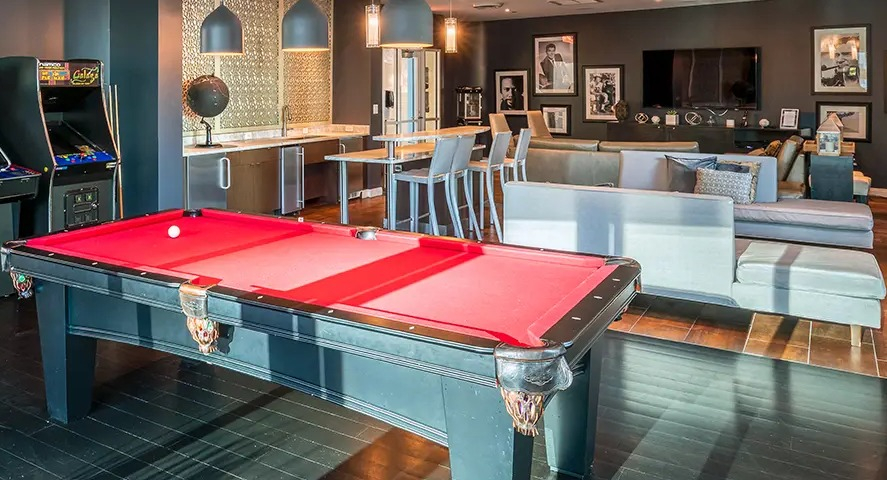 A vibrant game room featuring a billiards table, classic arcade games, and a lounge area for resident entertainment at The Streeter in Chicago