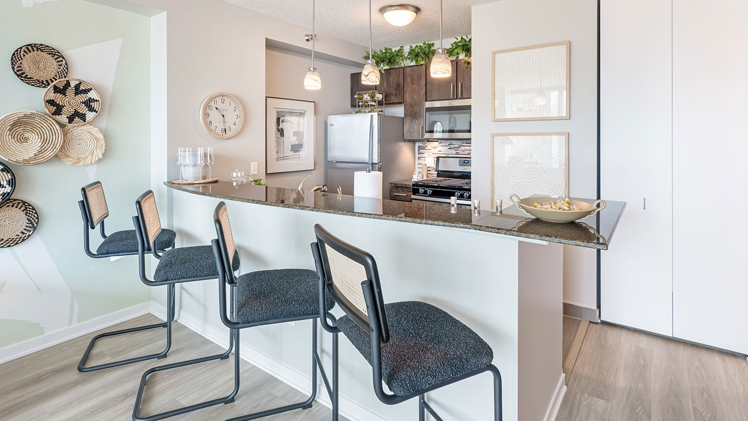 A contemporary kitchen with dark cabinetry, granite countertops, bar seating with stools, and stylish decorative accents at The Streeter in Chicago