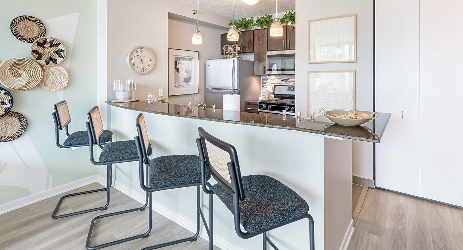 A contemporary kitchen with dark cabinetry, granite countertops, bar seating with stools, and stylish decorative accents at The Streeter in Chicago