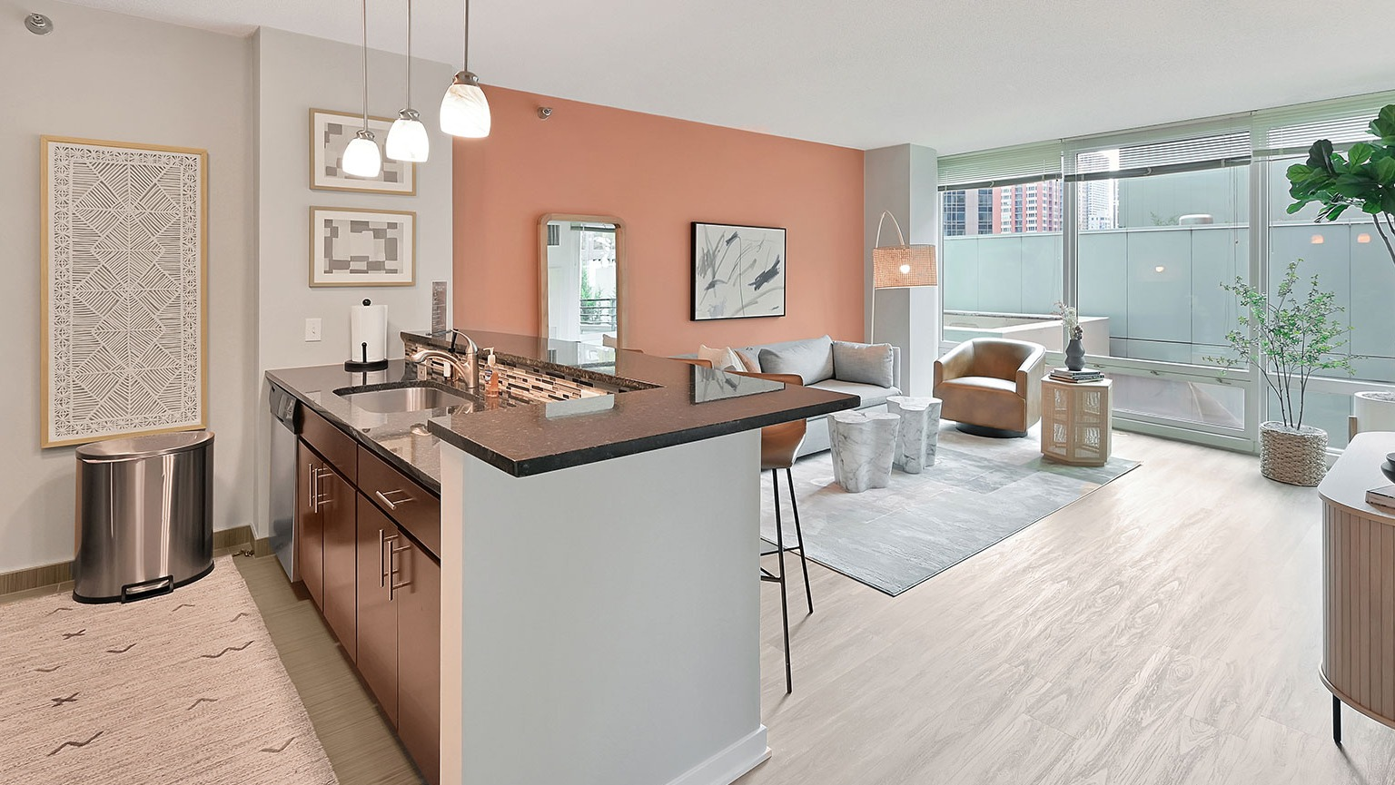 A stylish apartment with an open-concept modern kitchen featuring an island, and a vibrant living area with chic decor at The Streeter in Chicago