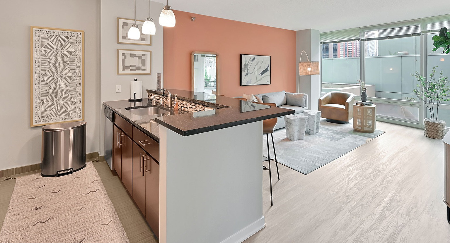 A stylish apartment with an open-concept modern kitchen featuring an island, and a vibrant living area with chic decor at The Streeter in Chicago