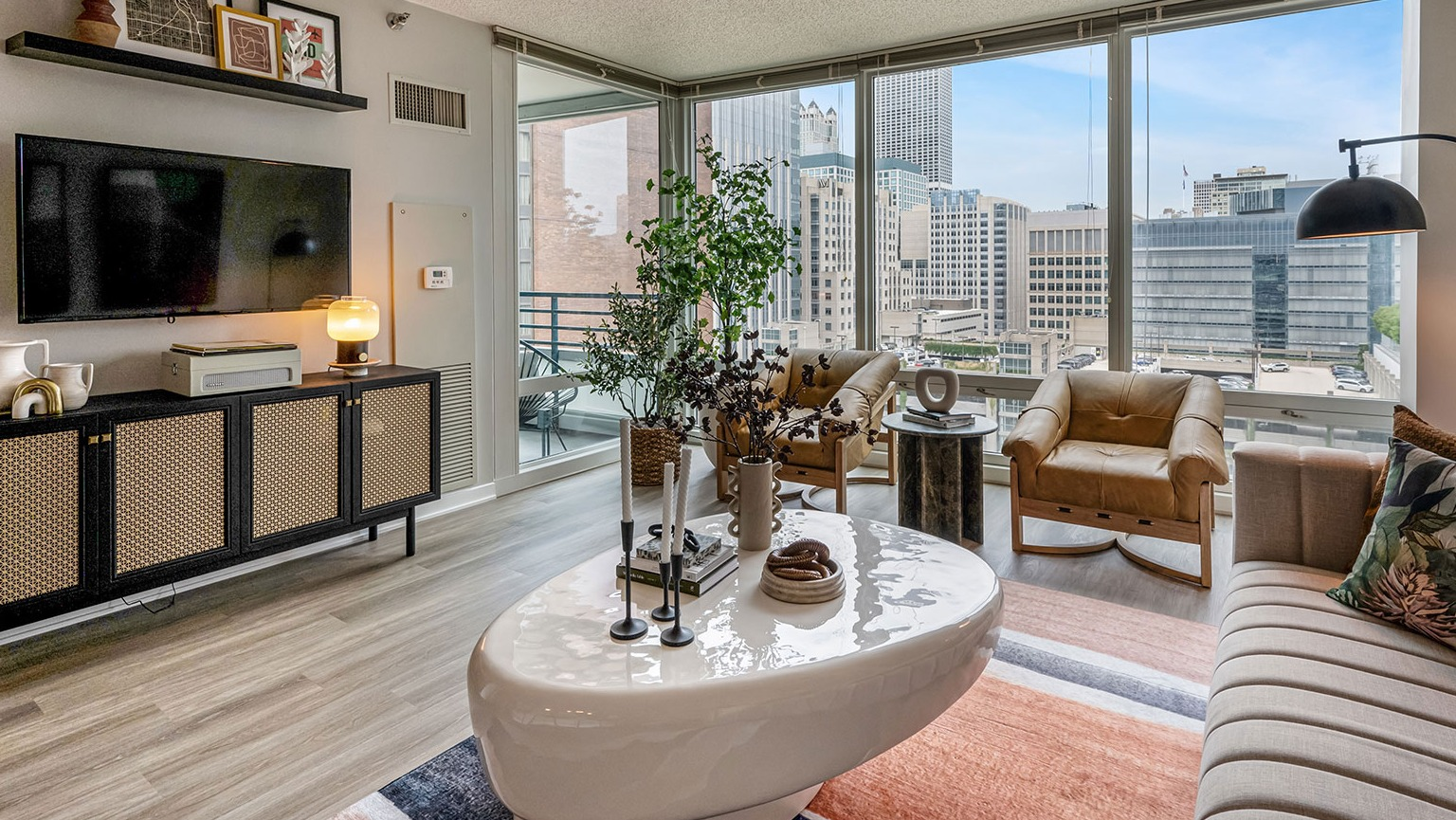A stylish modern living room with comfortable seating, sleek furniture, and expansive city views from large windows at The Streeter in Chicago