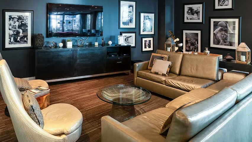 A cozy resident lounge doubling as a media room, featuring comfortable leather sofas and a large TV, adorned with classic photos at The Streeter in Chicago