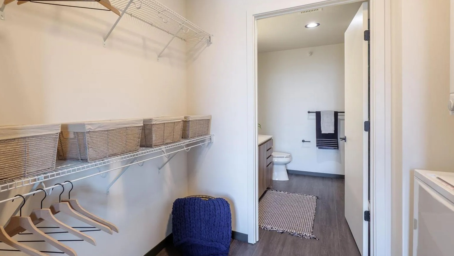 Spacious walk-in closet with ample shelving and a view of the adjacent bathroom and in-unit laundry at The Thompson at Fulton Market in Chicago