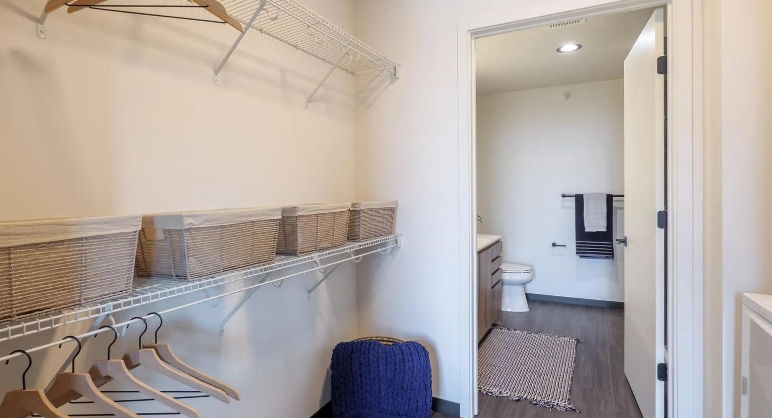 Spacious walk-in closet with ample shelving and a view of the adjacent bathroom and in-unit laundry at The Thompson at Fulton Market in Chicago