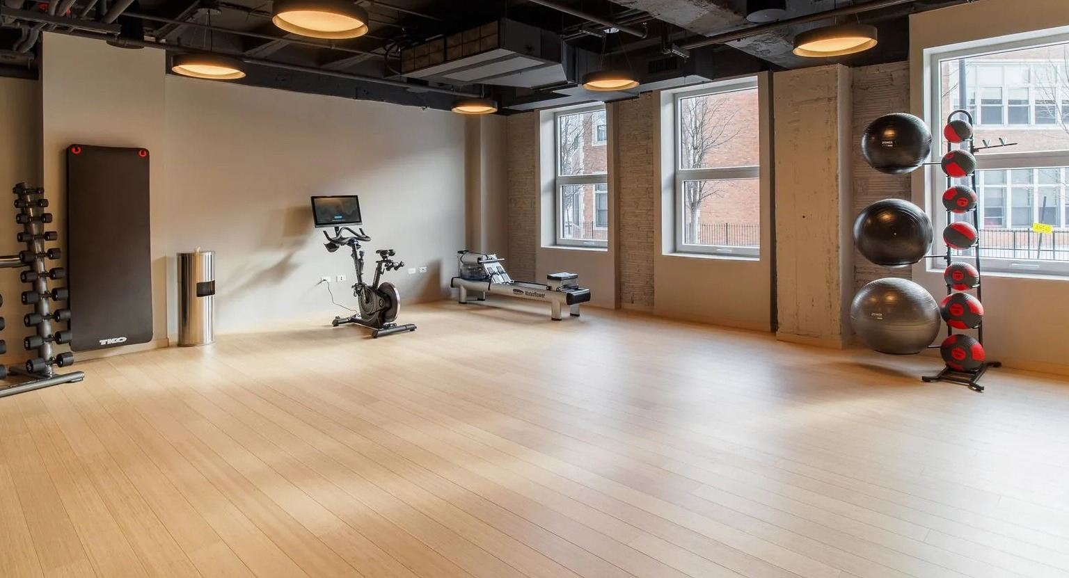 A bright and spacious fitness studio with hardwood floors, exercise bikes, and equipment for yoga or stretching at The Thompson at Fulton Market in Chicago