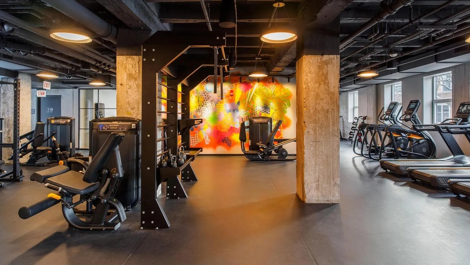 A comprehensive fitness center with various cardio machines, strength training equipment, and free weights at The Thompson at Fulton Market in Chicago
