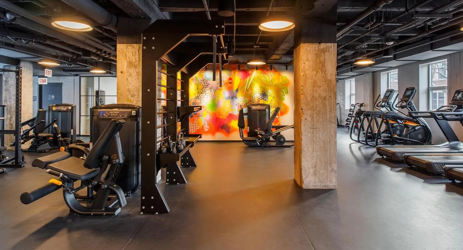 A comprehensive fitness center with various cardio machines, strength training equipment, and free weights at The Thompson at Fulton Market in Chicago
