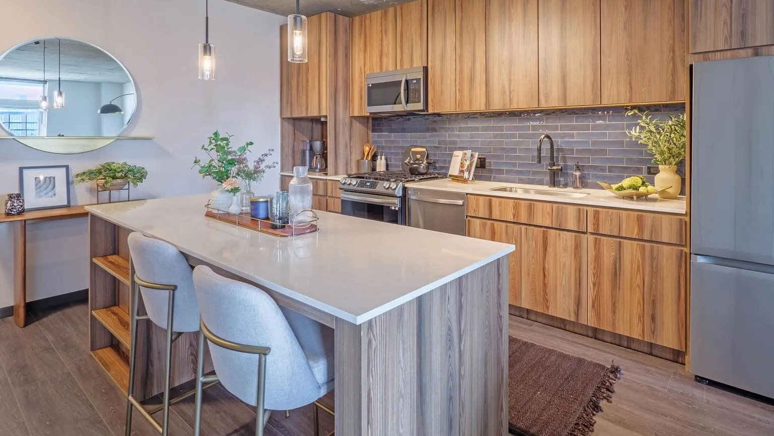 Modern kitchen with a large island, wood cabinetry, stainless steel appliances, and stylish pendant lighting at The Thompson at Fulton Market in Chicago
