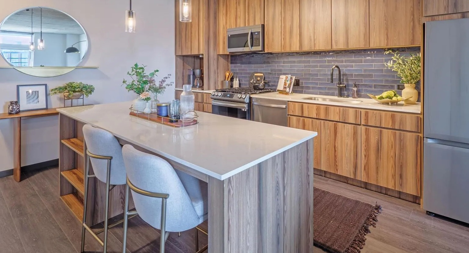 Modern kitchen with a large island, wood cabinetry, stainless steel appliances, and stylish pendant lighting at The Thompson at Fulton Market in Chicago