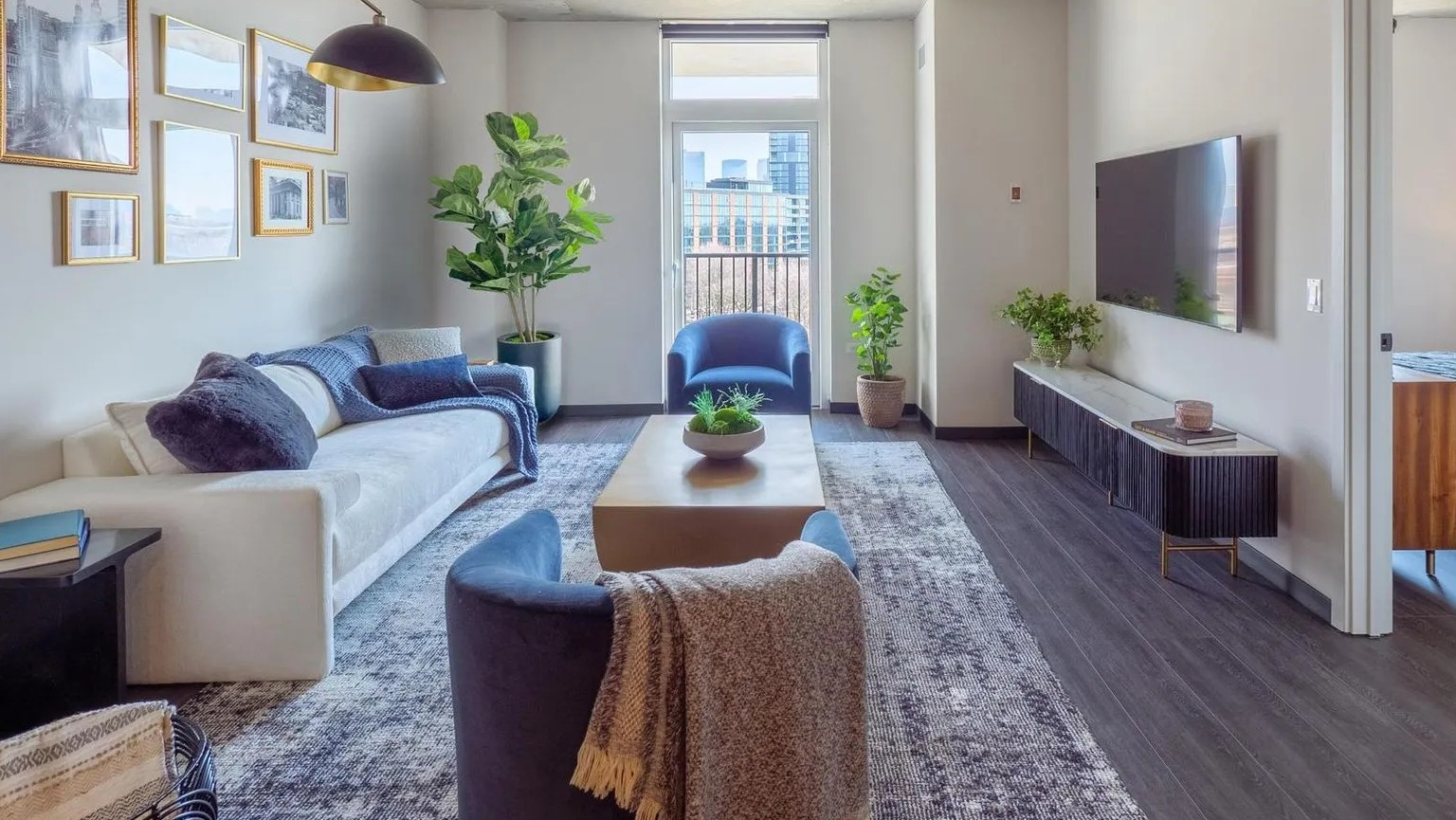 Bright open-concept living room with modern furniture, curated artwork, and large windows offering city views at The Thompson at Fulton Market in Chicago