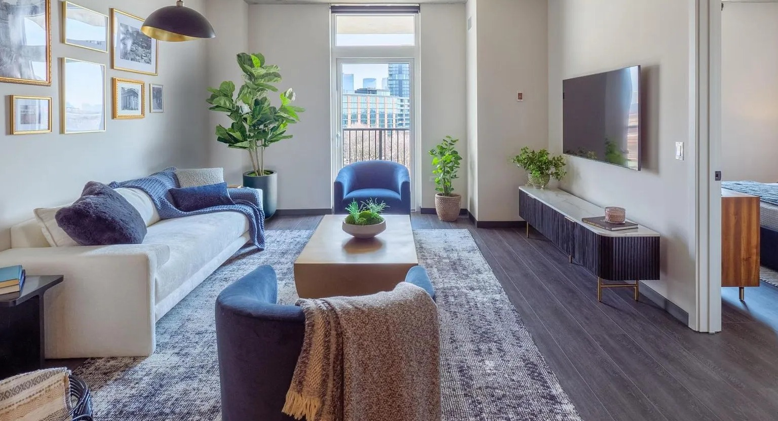 Bright open-concept living room with modern furniture, curated artwork, and large windows offering city views at The Thompson at Fulton Market in Chicago