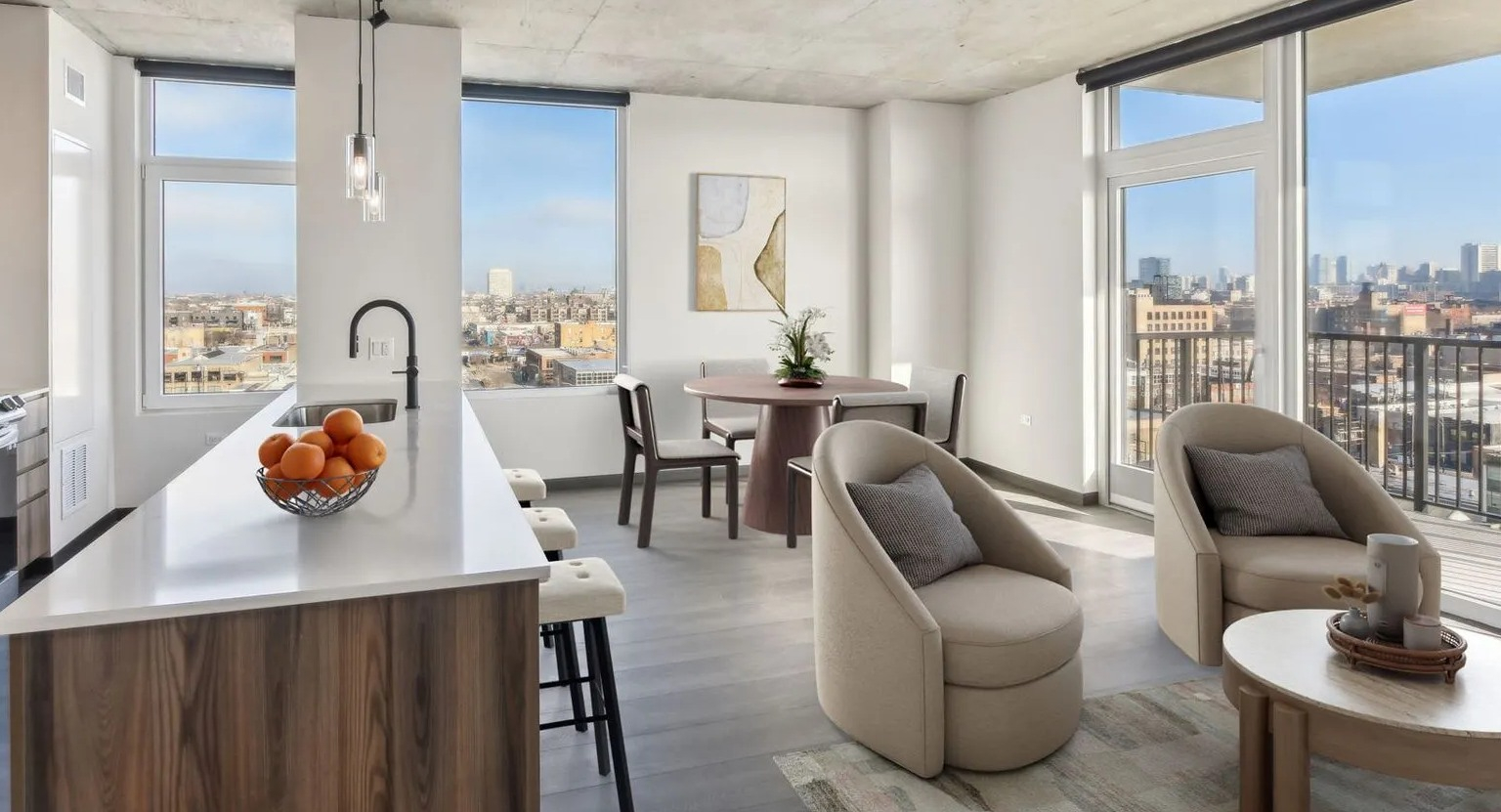 A bright open-concept apartment with a modern kitchen island, dining area, and a spacious living room with city views at The Thompson at Fulton Market in Chicago