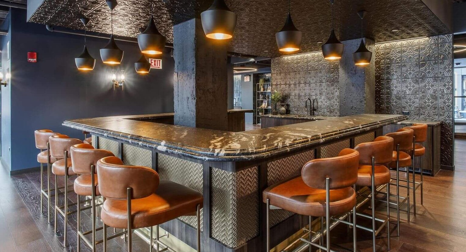A luxurious resident bar and lounge area with stylish bar stools, intricate ceiling design, and a sophisticated ambiance at The Thompson at Fulton Market in Chicago