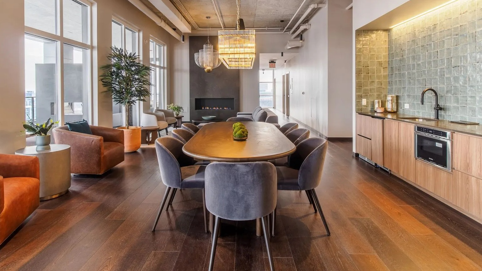 A sophisticated resident lounge with a long dining table, comfortable armchairs, and a modern fireplace at The Thompson at Fulton Market in Chicago