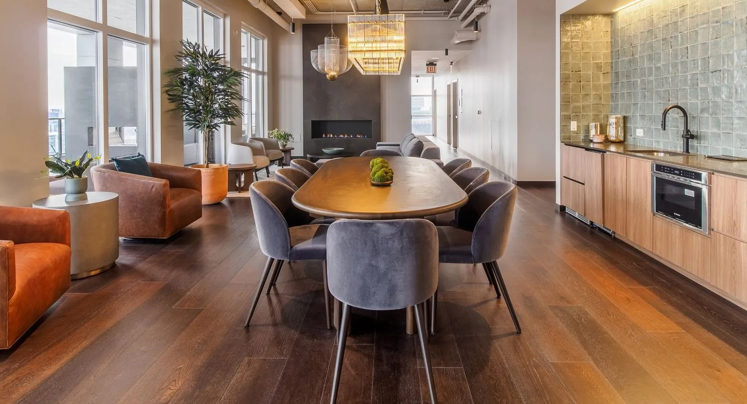 A sophisticated resident lounge with a long dining table, comfortable armchairs, and a modern fireplace at The Thompson at Fulton Market in Chicago