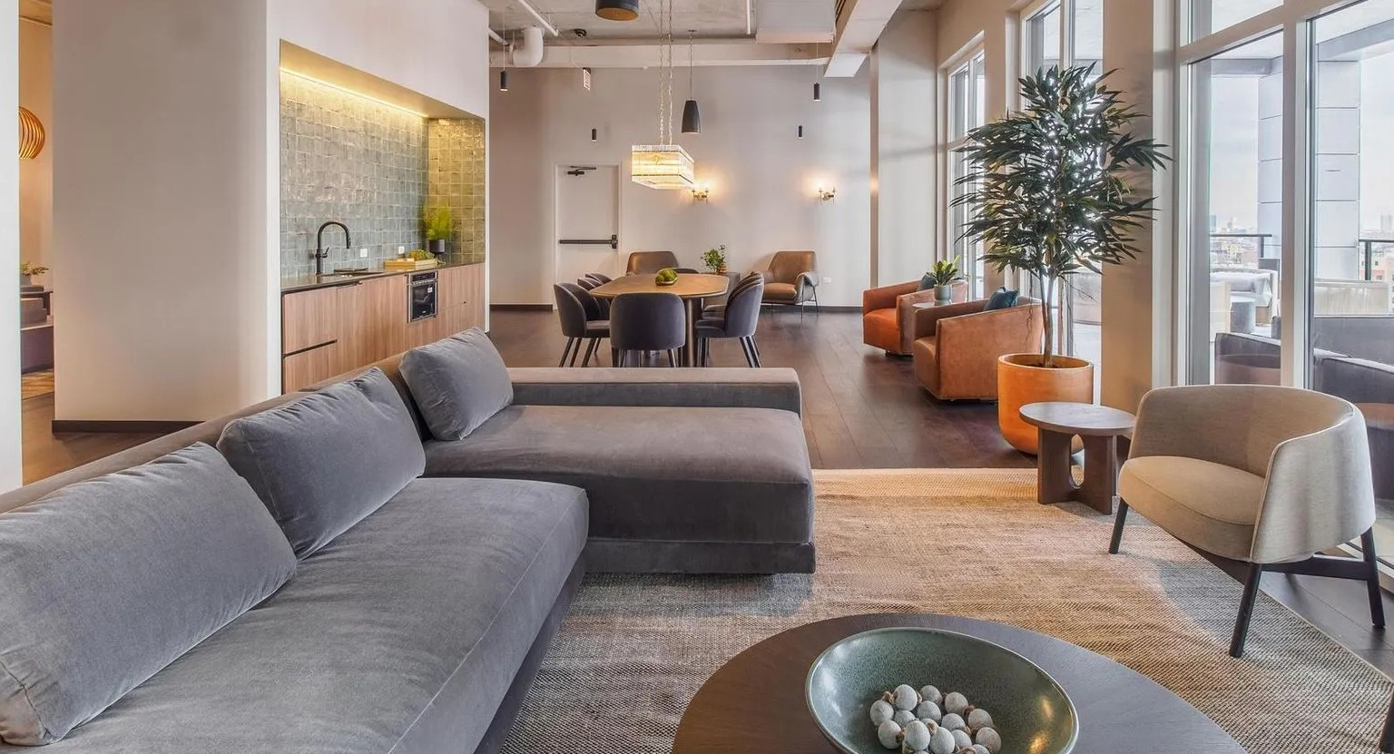 A stylish resident lounge with comfortable seating, a dining area, and a modern kitchen space at The Thompson at Fulton Market in Chicago