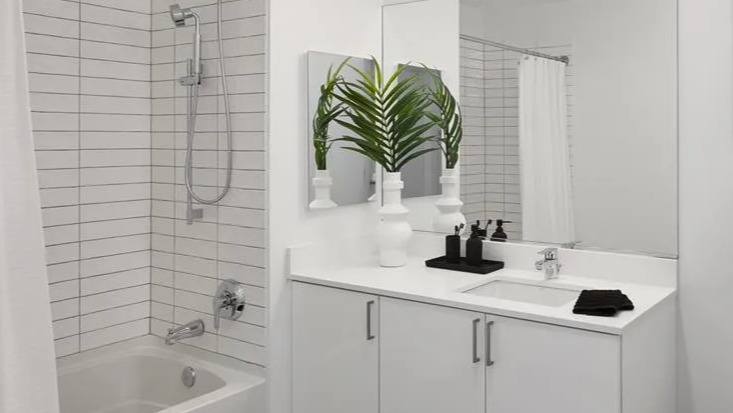 Modern bathroom at The Van Buren apartments in Chicago with a white subway tiled shower and sleek vanity