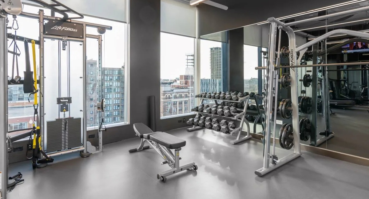 Well-equipped gym area featuring various weight training machines, free weights, and ample space for strength workouts at The Van Buren in Chicago