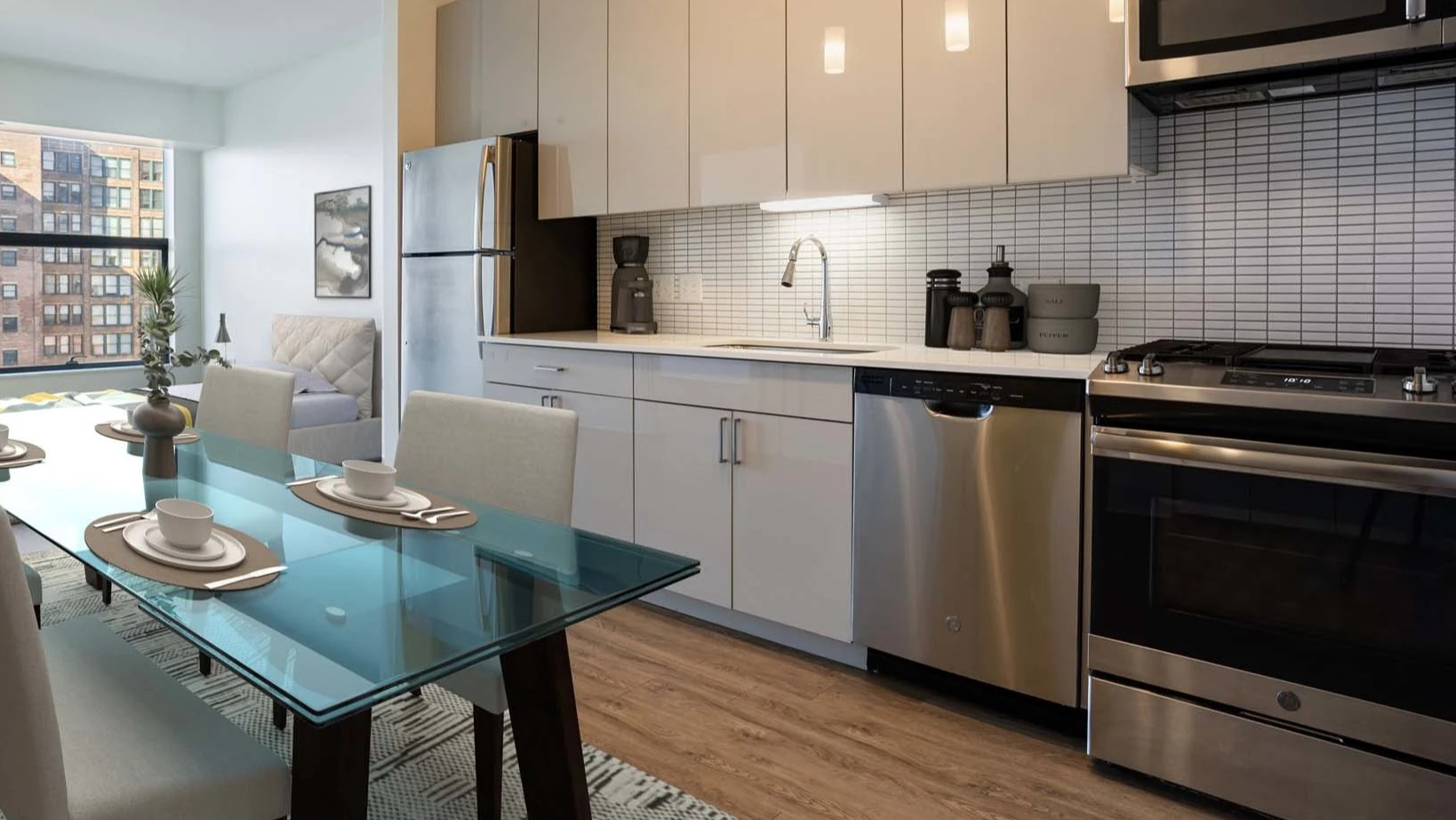 Contemporary kitchen and dining area at The Van Buren apartments, featuring stainless steel appliances and pendant lighting