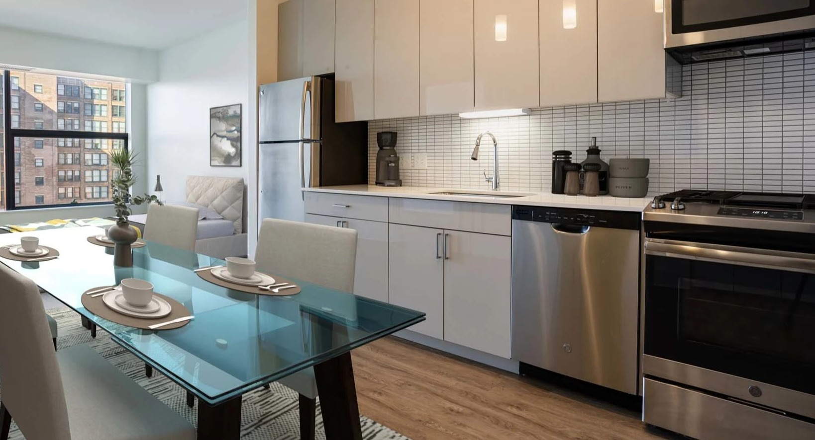 Contemporary kitchen and dining area at The Van Buren apartments, featuring stainless steel appliances and pendant lighting