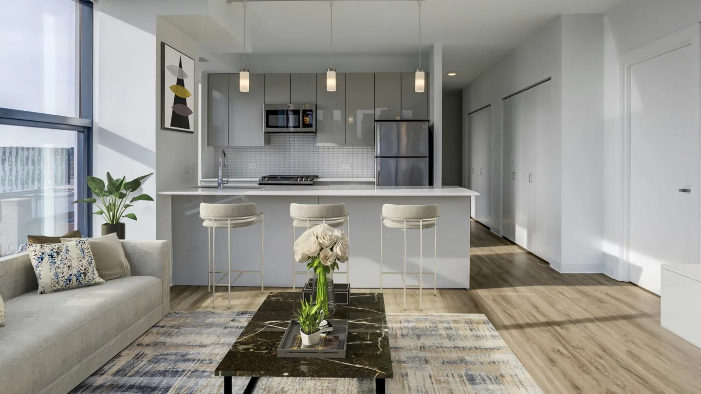 Bright open-plan kitchen and living room with a breakfast bar and large windows at The Van Buren apartments in Chicago