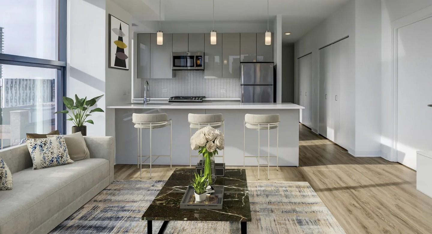 Bright open-plan kitchen and living room with a breakfast bar and large windows at The Van Buren apartments in Chicago