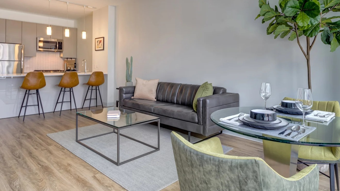 Modern apartment showcasing a spacious dining area with a glass table, open to a sleek kitchen at The Van Buren in Chicago