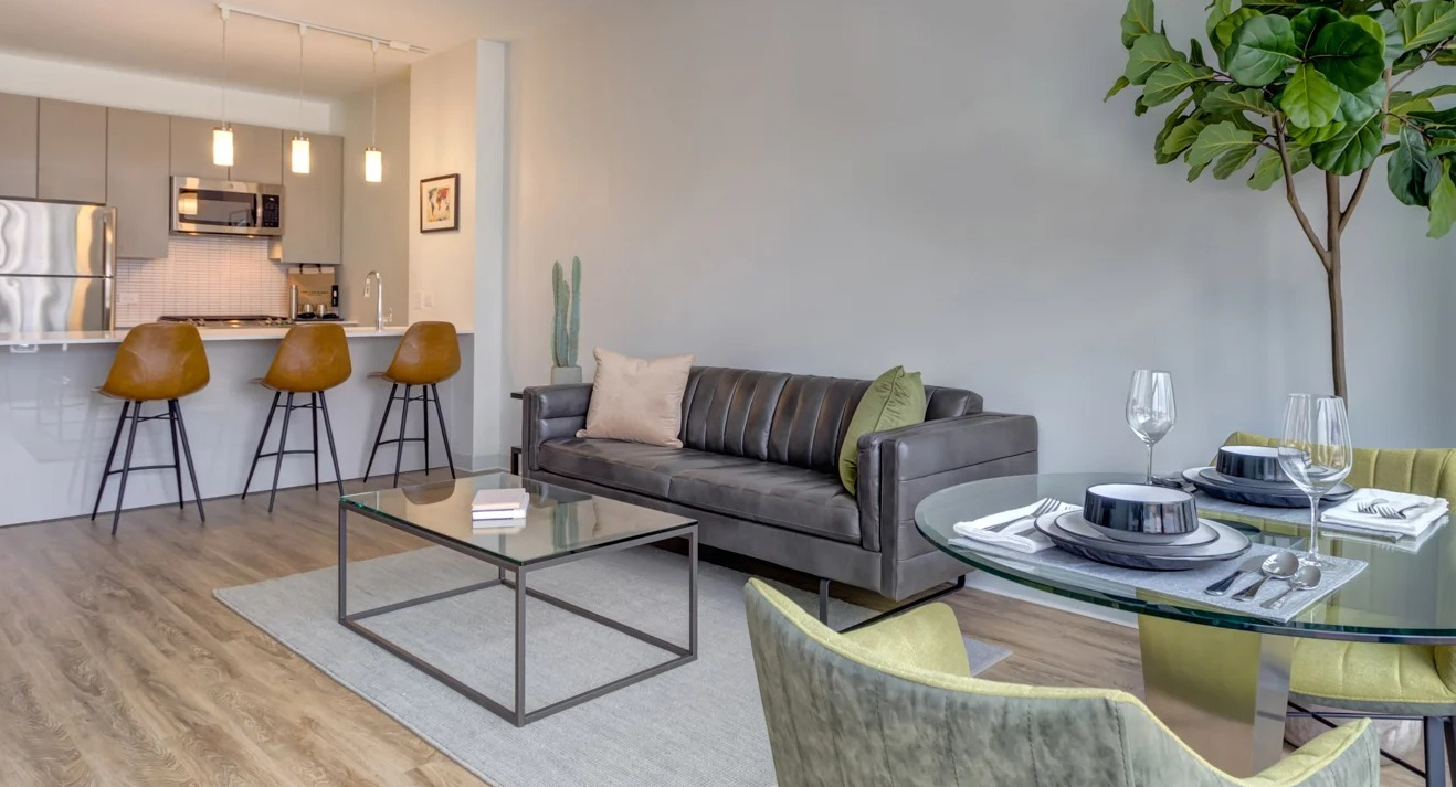 Modern apartment showcasing a spacious dining area with a glass table, open to a sleek kitchen at The Van Buren in Chicago