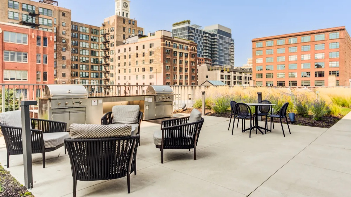 Outdoor rooftop grilling area with seating and views of historic Chicago architecture at The Van Buren apartments