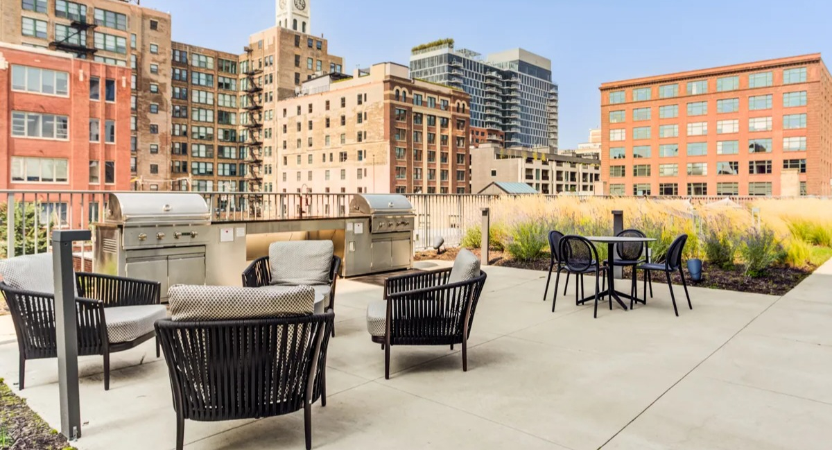 Outdoor rooftop grilling area with seating and views of historic Chicago architecture at The Van Buren apartments