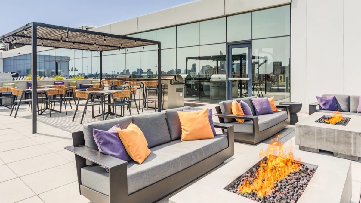 Luxurious rooftop lounge at The Van Buren apartments with multiple fire pits, comfortable seating, and BBQ grills in Chicago