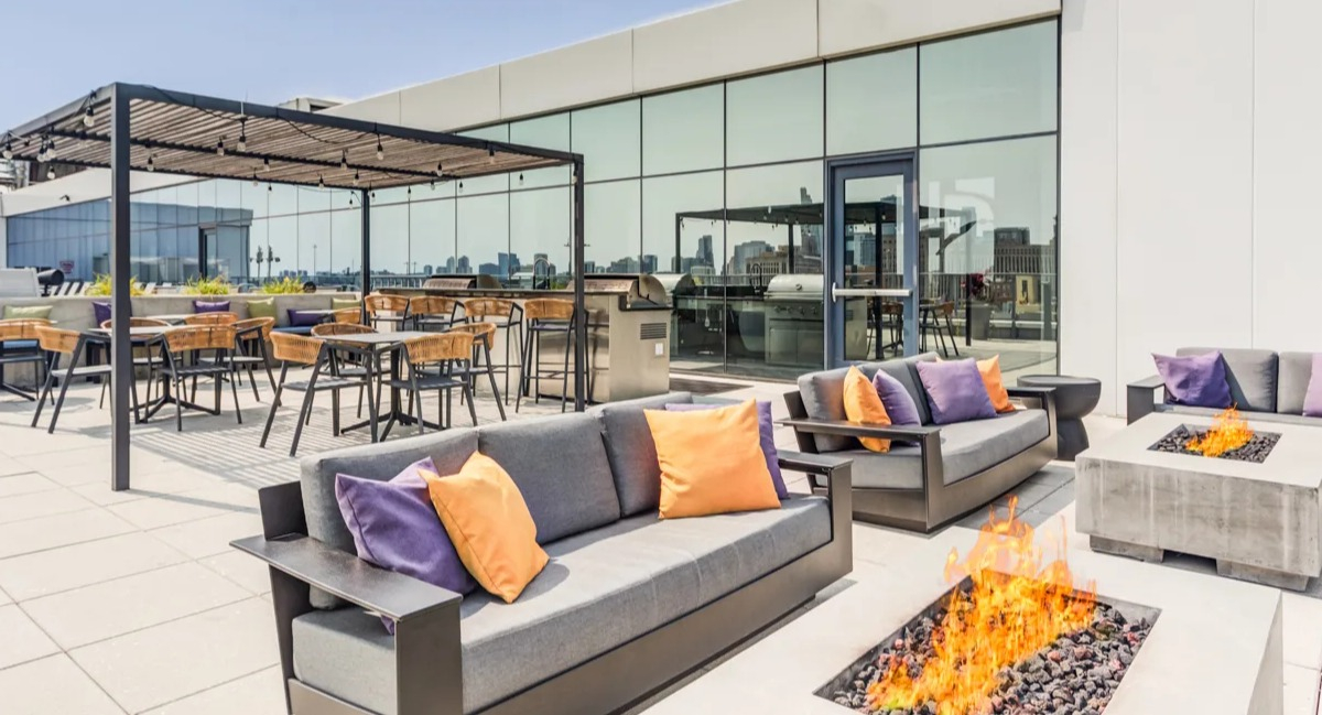 Luxurious rooftop lounge at The Van Buren apartments with multiple fire pits, comfortable seating, and BBQ grills in Chicago
