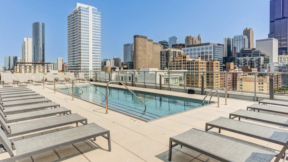 Inviting rooftop swimming pool at The Van Buren apartments, surrounded by lounge chairs and stunning Chicago city views