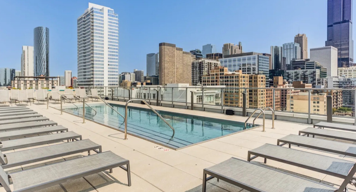Inviting rooftop swimming pool at The Van Buren apartments, surrounded by lounge chairs and stunning Chicago city views