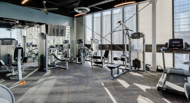 Spacious gym at Trio Apartments in Chicago, offering a variety of workout machines and panoramic city views