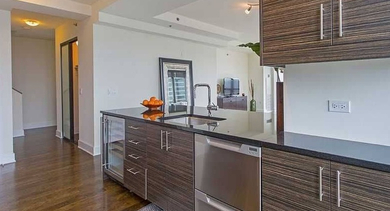 Elegant kitchen featuring dark wood cabinetry, a functional island, and a spacious hallway leading to other areas at Trio Apartments in Chicago