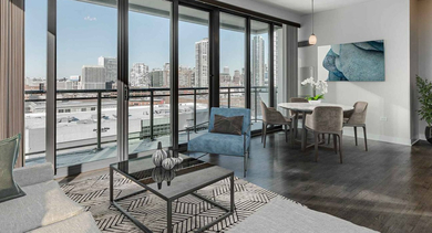 Elegant living room with comfortable seating, a dining area, and access to a private balcony with city views at Trio Apartments in Chicago